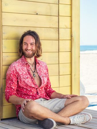 Cheerful guy sitting near blue wall