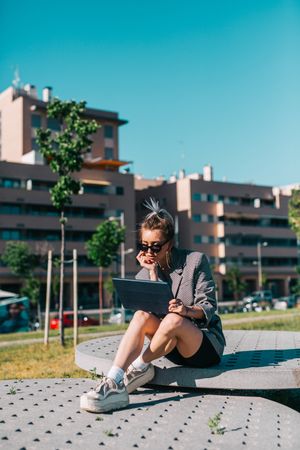 Stylish woman sitting and browsing tablet outside