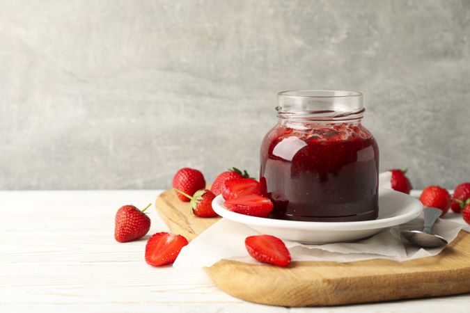Composition with strawberry jam on wooden table against gray background