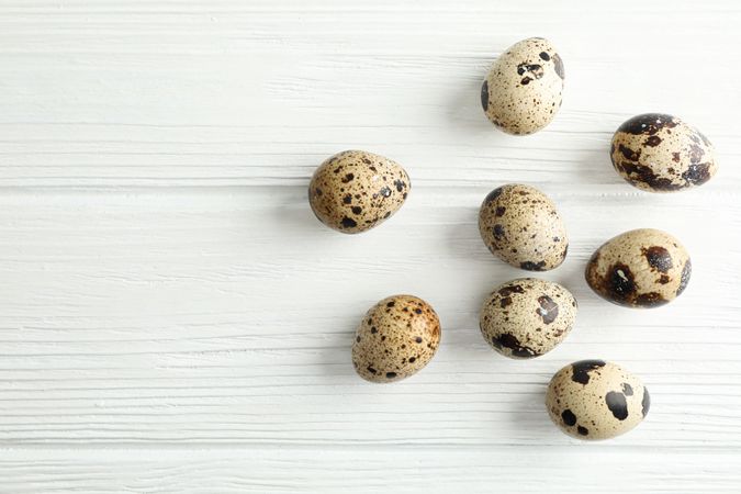 Flat lay composition with quail eggs on wooden background, space for text