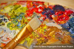 Paint brush lying on paint palette with rich colors 41ZKOb