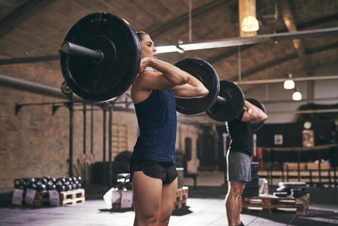 Two gym trainers exercising with barbells and weights