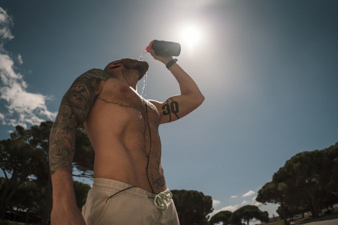 Shirtless man drinking during training