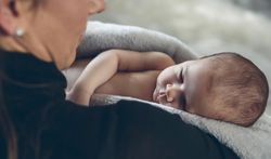 Baby wrapped embraced by her mother