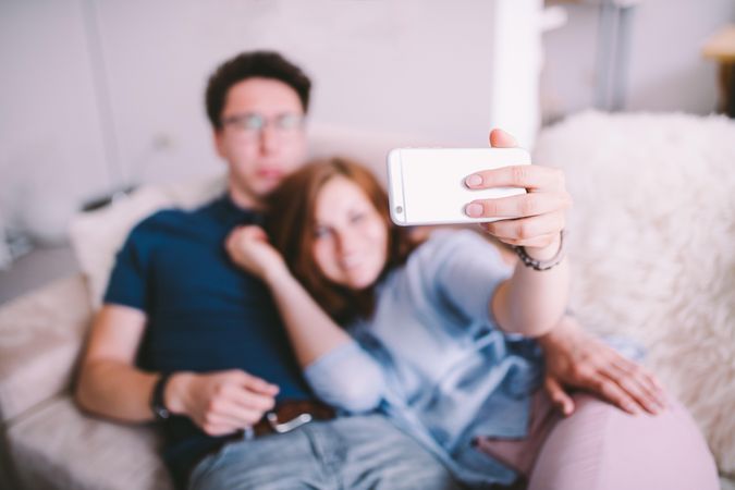 Young woman and man take a selfie on a couch