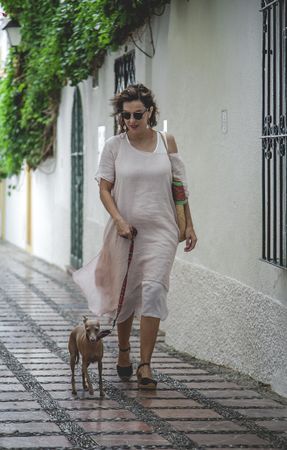 Woman walking with dog on narrow street
