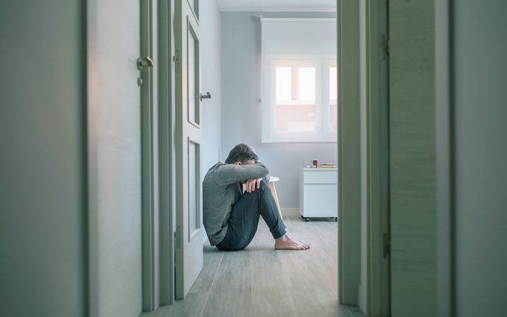 Man crying sitting on room floor