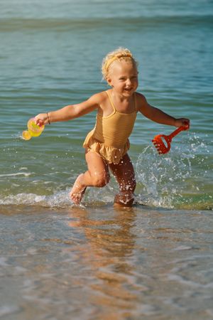 Adorable blonde girl playing in water and toys