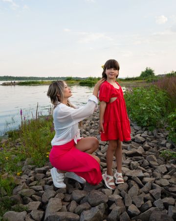 Mom and little daughter walking by the lake or pond