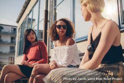 Multiracial group of young women sitting outdoors and chatting 5p3vv0