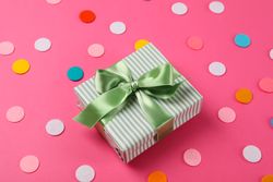 Gift box with bow on pink background, space for text