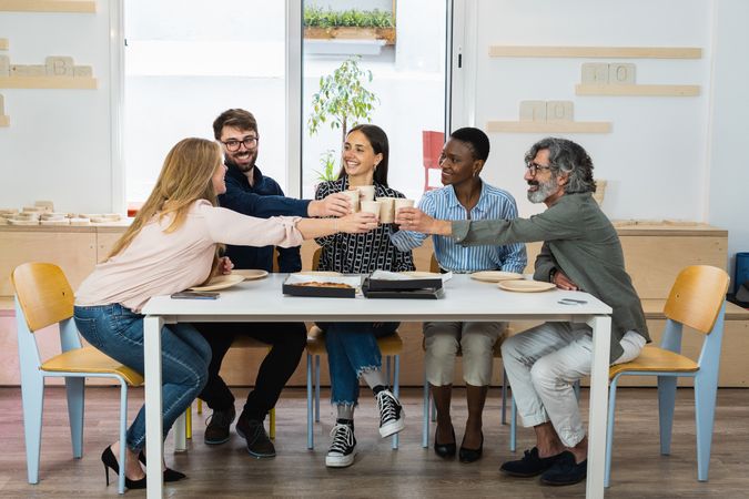 Diverse colleagues having lunch together in kitchen of office