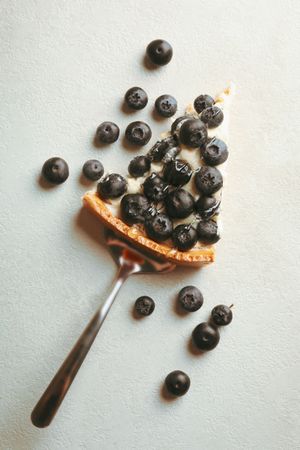 Spatula with blueberry pie slice on gray background