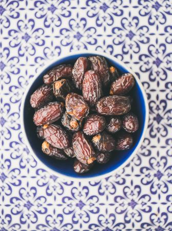 Top view bowl of dates on blue tiled surface