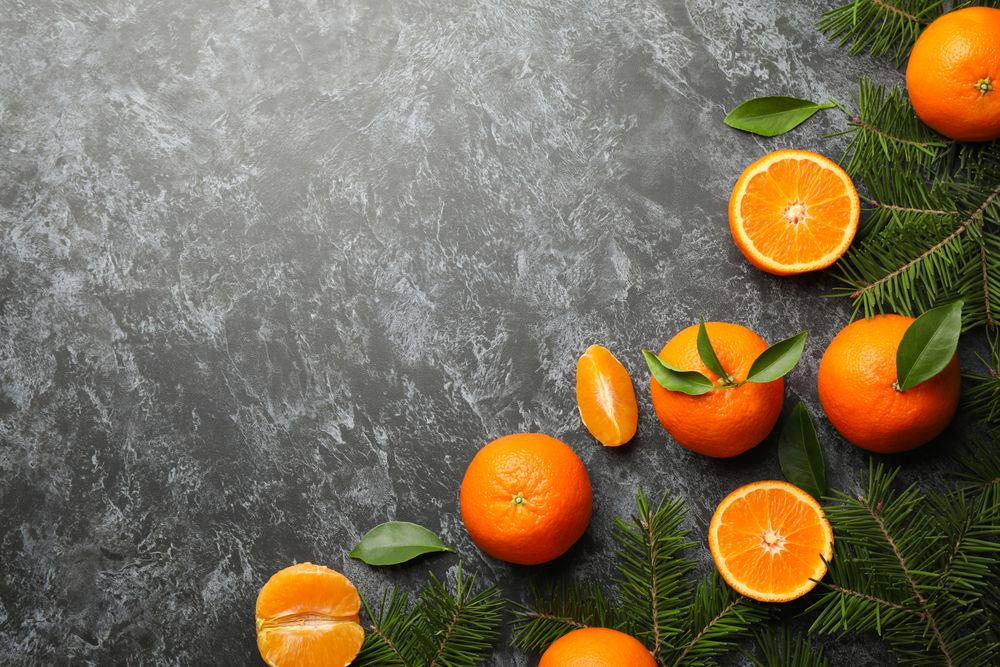 Mandarins and pine branches on gray smoky background