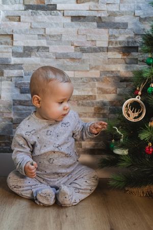 Cute baby playing with Christmas tree baubles