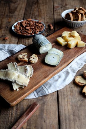 Croutons and nuts near board with cheese