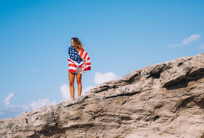 Peaceful patriotic female traveler enjoying in vacation at rocks
