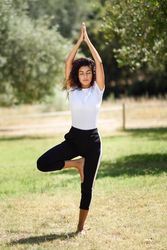 Arab woman doing one legged yoga pose in park