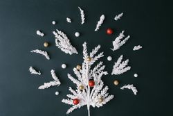 Christmas tree branches in tree shape with bauble decorations on dark table background