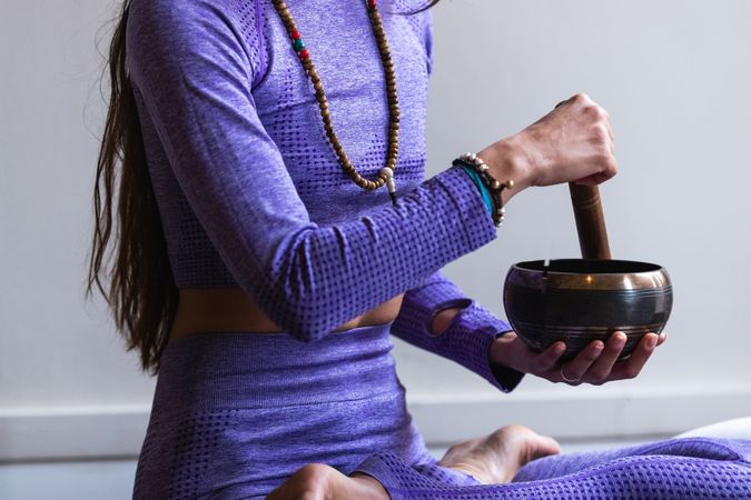 Anonymous woman playing singing bowl during yoga session