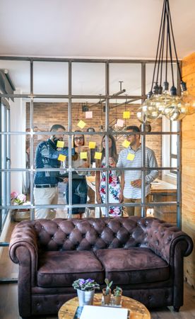 Business people in a work meeting placing sticky notes on the wall
