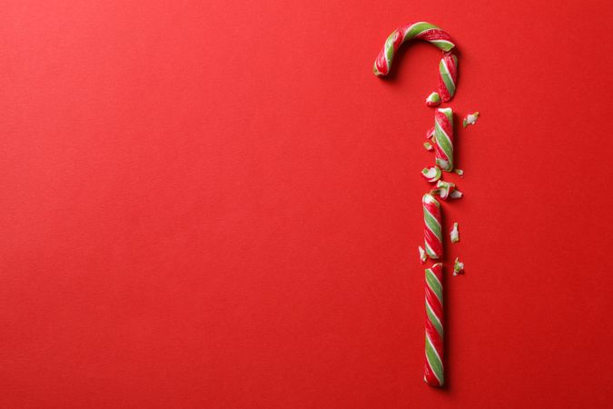 Broken candy cane on red background, space for text