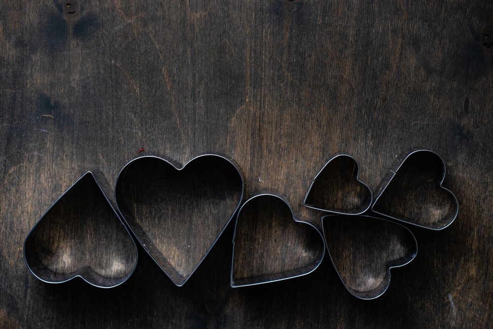 Heart shaped cookie cutters in line on wooden table