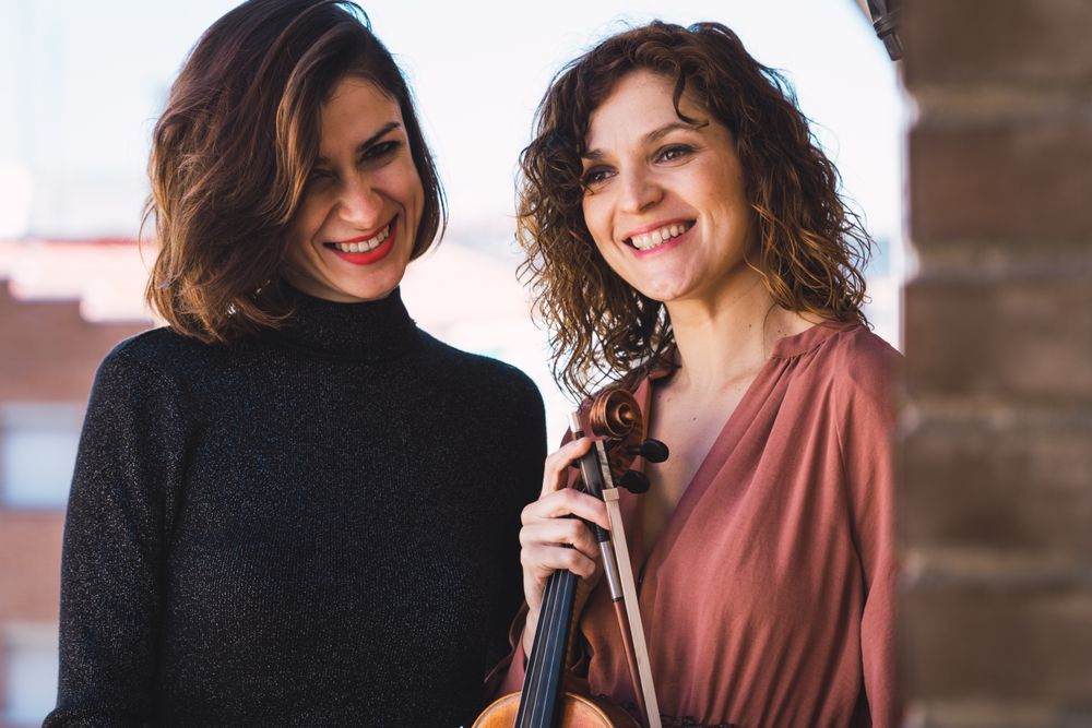 Young smiling women with violin on balcony
