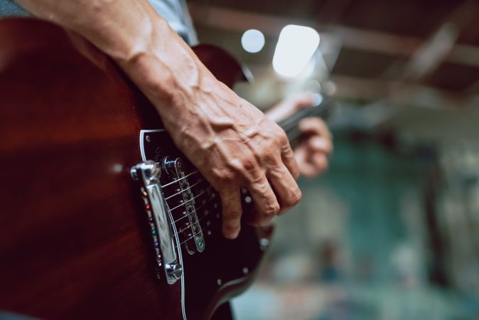 Man clamping strings on guitar neck