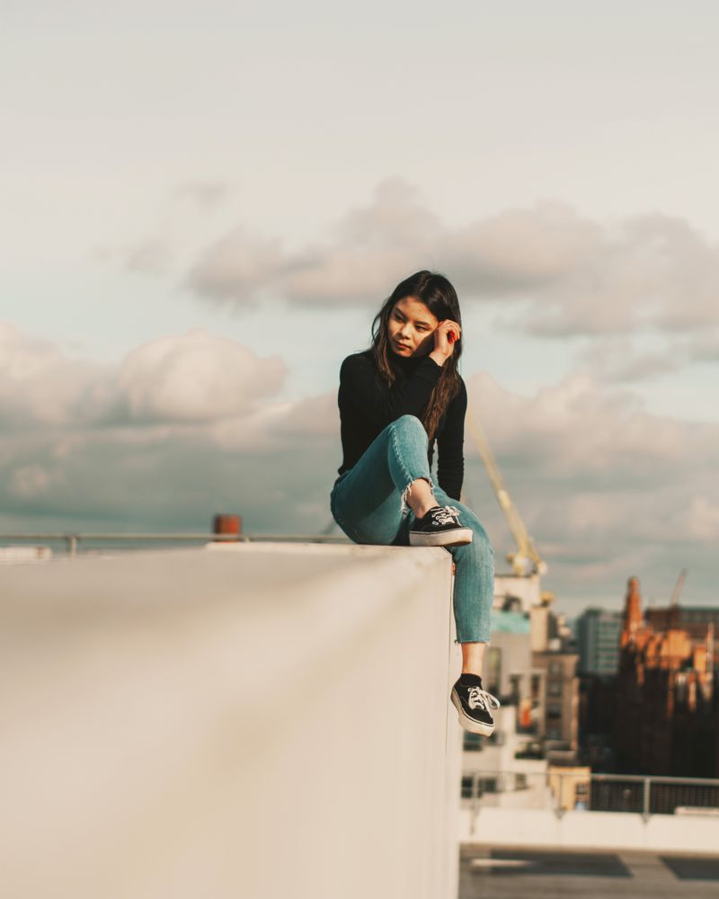 Girl sitting on  concrete wall on a rooftop