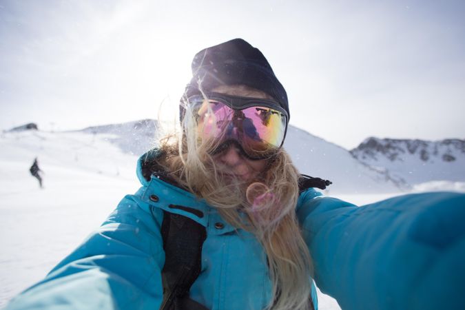 Woman in skiing gear taking selfie on cold day in the mountains