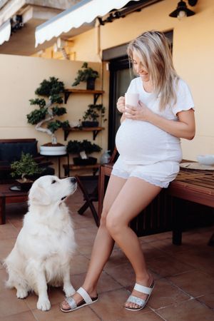 Pregnant woman having breakfast with dog
