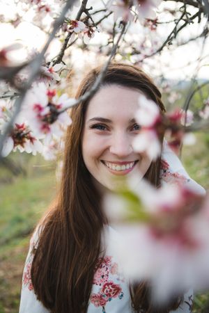 Young happy woman between trees in garden