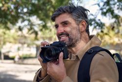 Mature gray haired man with photo camera in park