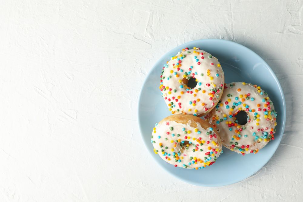 Plate with tasty donuts on plain background