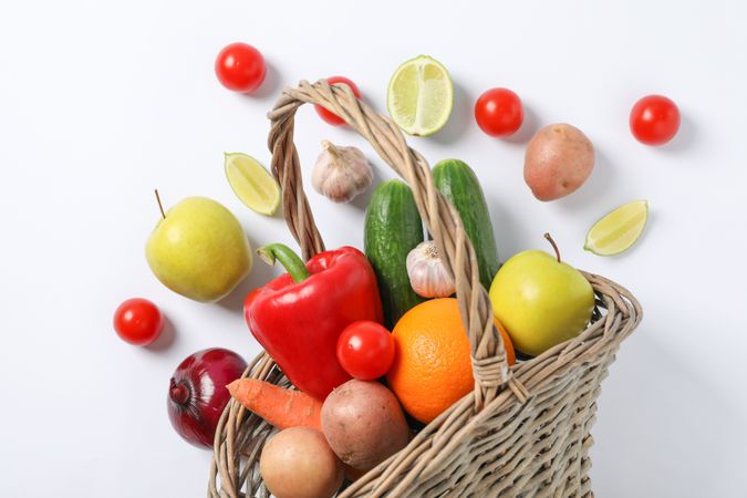 Wicker basket, vegetables and fruits on background, space for text