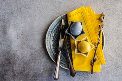 Top view of Easter table setting with yellow plate and pastel ornaments