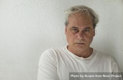 Portrait of sad middle aged man in light shirt against light wall bxKXd4