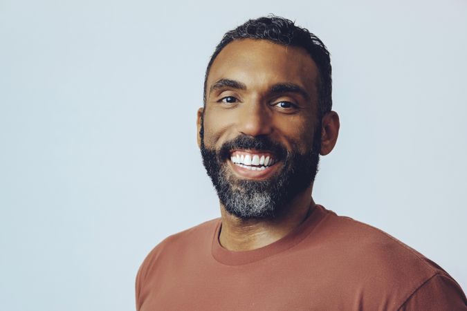 Head shot of smiling Black male in grey studio, copy space
