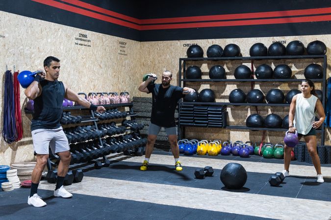 Hispanic sportspeople lifting kettlebells in gym