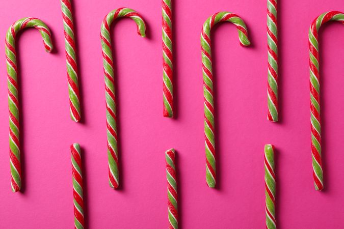 Flat lay composition with candy canes on pink background, close up