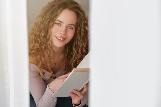 Smiling female reading book and looking at camera