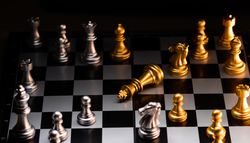 Fallen gold king in a strategic chess match. Checkmate.