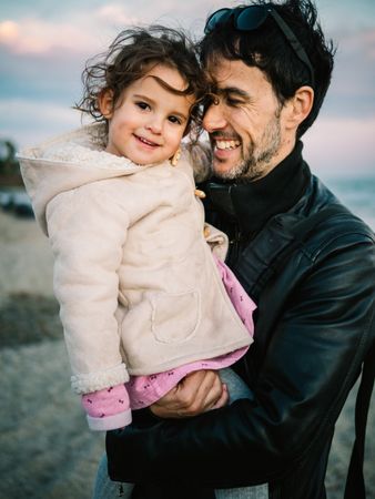 father holding little daughter at the beach
