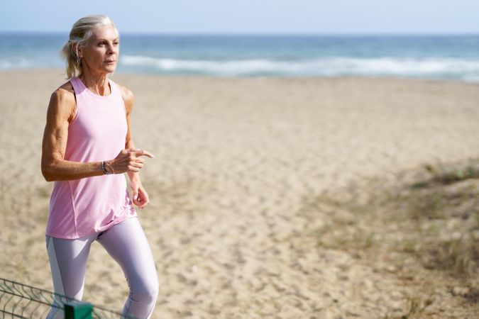 Healthy mature woman in sports gear running along beach