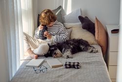 Boy with retro photo camera and Miniature Schnauzer on bed