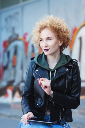 Curly haired female in leather jacket outdoors