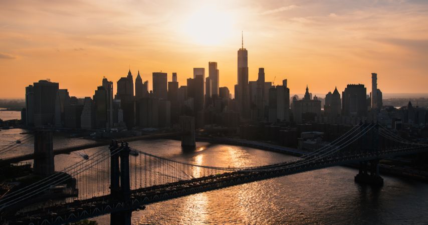 New York City Skyline Aerial Shot from a Helicopter at Sunset. Famous Skyscraper Buildings with Manhattan and Brooklyn Bridges. Busy Diverse Megapolis with Cars, Boats and People Moving Around