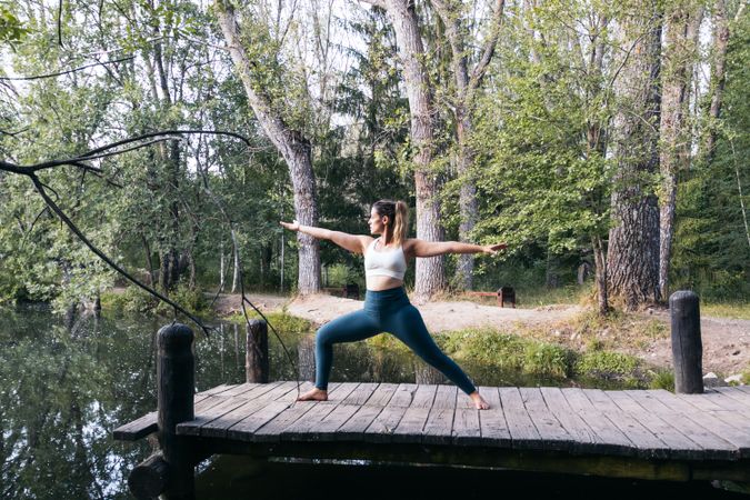 Woman in sportswear doing yoga in nature near a lake